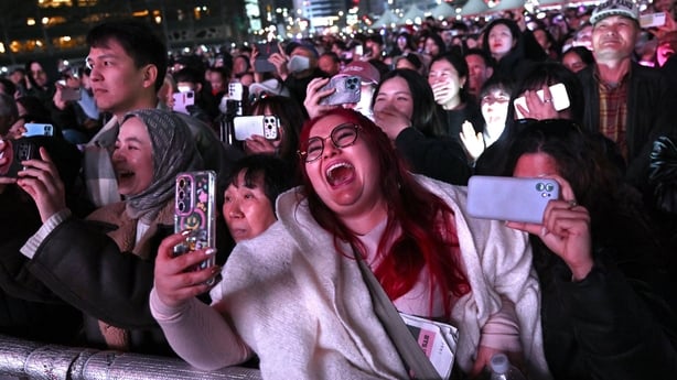 BTS fans react as they watch the comeback concert of K-pop boy group BTS on a screen at the venue in Seoul on March 21, 2026. South Korean megastars BTS reunited on 21 March for their first show in nearly four years. (Photo by Jung Yeon-je / AFP)