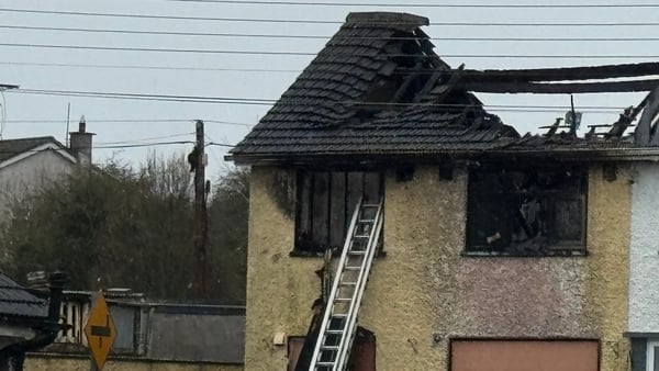 image shows a badly burned out house with a ladder leaning against it