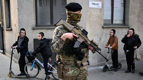 Members of the Jewish community walk past Belgian military personnel armed with FN SCAR assault rifles standing guard in central Antwerp