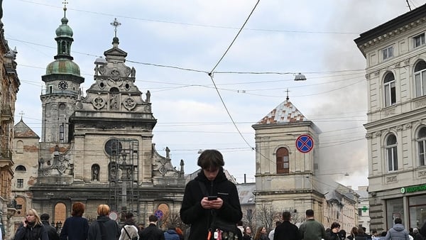 People look at smoke rising from a burning building following a Russian drone attack in Lviv