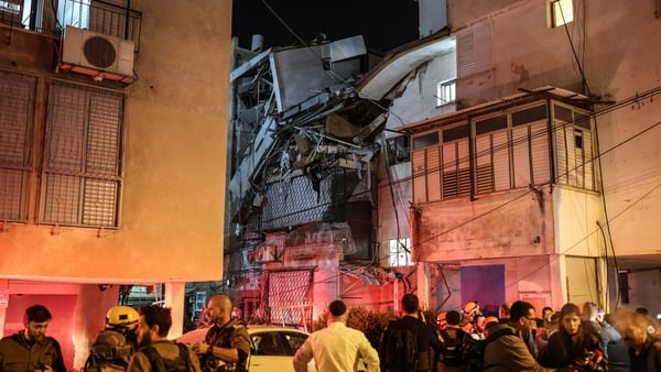 Security forces and first responders gather next to a damaged building at a site struck by a projectile in Bnei Brak, on the eastern outskirts of Tel Aviv