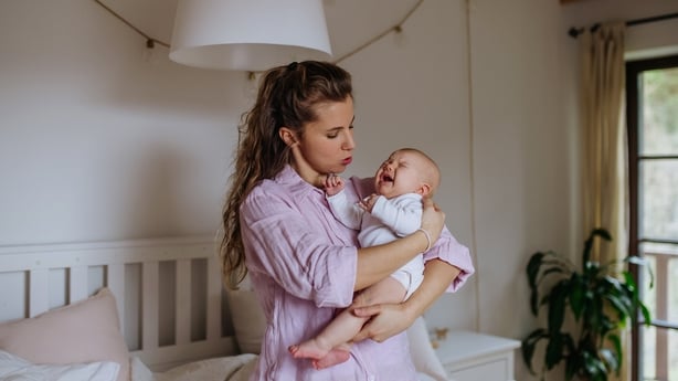 Mother holding crying newborn baby. Little baby is fussy, colic baby. Stressful frustrating moment for new mom.