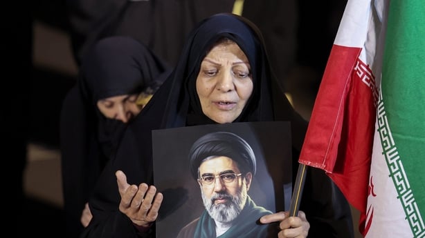A woman holds a portrait of Iran's supreme leader Mojtaba Khamenei as people march in support of the Iranian armed forces in central Tehran on March 25, 2026. President Donald Trump is ready to "unleash hell" if Iran doesn't accept a deal to end the Middle East war,