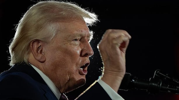 US President Donald Trump speaks at a podium during a committee fundraiser
