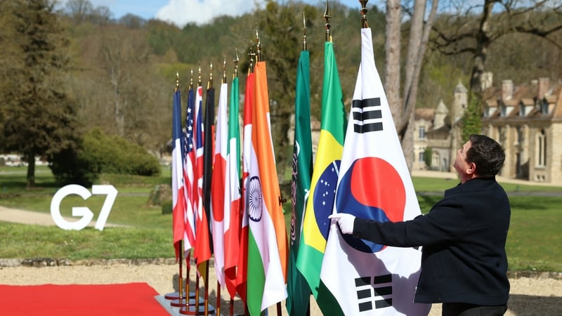 a man hangs a flag on a flagpole with other flags in a line
