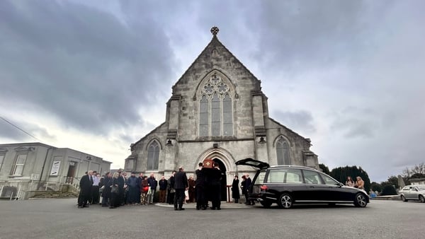 Mourners gather outside a church for the funeral of Michael Lyster in Dublin
