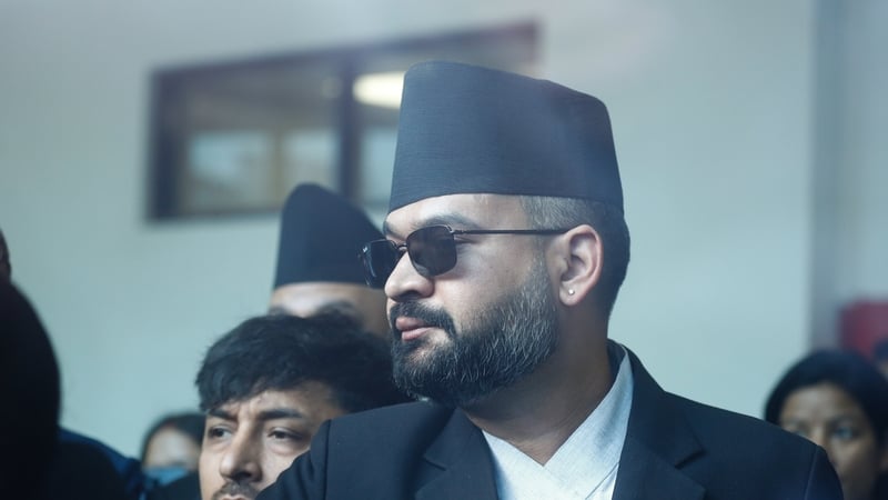 A man wearing sunglasses and a black nepali cloth hat