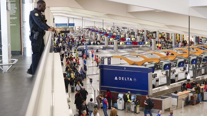 A police officer looks down on an airport concourse where hundreds of people are queueing