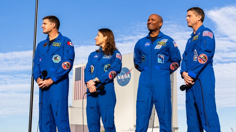 Three men and a woman in NASA jumpsuits are photographed