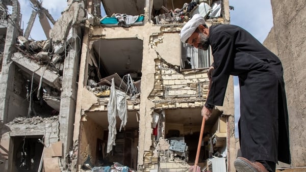 A man sweeps up debris near a residential building that was hit in an airstrike in the early hours in Tehran, Iran