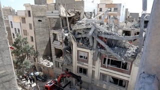 Firefighters look for victims and inspect damages at a residential building in southern Tehran