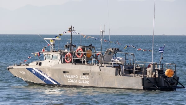 A Hellenic Coast Guard vessel LS 135 / ?? 135 as seen patrolling in the waters of The Thermaic Gulf or Gulf of Salonika with the celebration flags and symbols during Epiphany day in Thessaloniki while young men and women dive into the sea to catch the cro