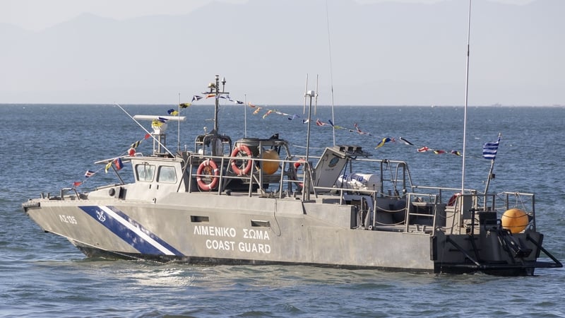 A Hellenic Coast Guard vessel LS 135 / ?? 135 as seen patrolling in the waters of The Thermaic Gulf or Gulf of Salonika with the celebration flags and symbols during Epiphany day in Thessaloniki while young men and women dive into the sea to catch the cro