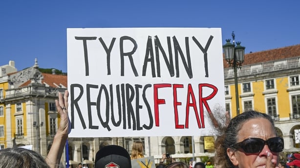 LISBON, PORTUGAL - MARCH 28: U.S. nationals residing in Portugal hold placards while gathering in Praça do Comercio at a protest organized by American activists living in Portugal, during a "No Kings" protest against U.S. President Donald Trump on March 28, 2026 in Lisbon, Portugal. No Kings protest
