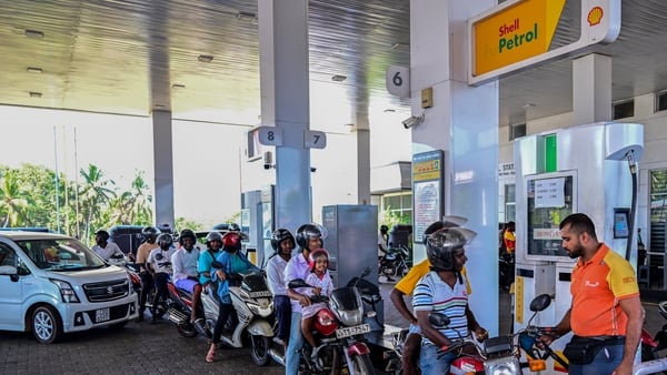 People wait in a queue to refuel their vehicles at a filling station in Biyagama on the outskirts of Colombo