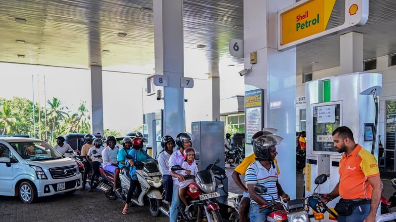 People wait in a queue to refuel their vehicles at a filling station in Biyagama on the outskirts of Colombo
