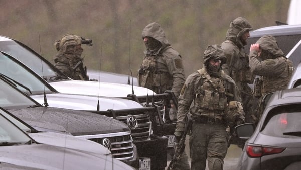 Heavily armed police gather at a staging point during a search for a fugitive linked to the murder of two police officers, in Porepunk