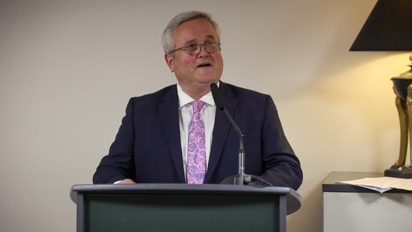 John Stephens in front of a microphone at a lecturn