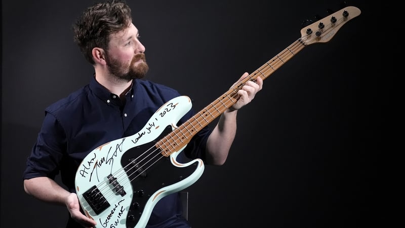 Propstore employee holds Motley Crue Nikki Sixx's photo-matched autographed and inscribed stage used Schecter J-4 Bass Guitar