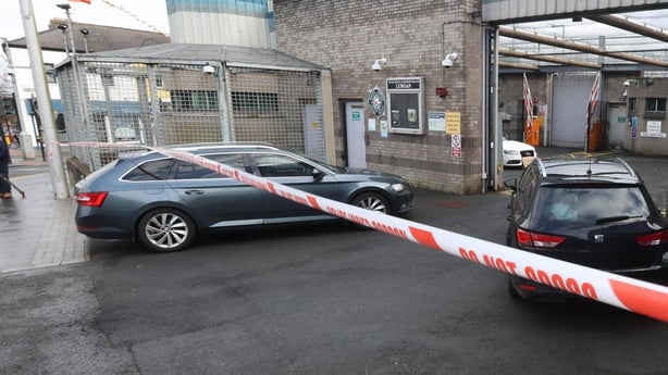 The bonnet of a white audi can be seen inside the gates of a police station with a police tape strung across the entrace