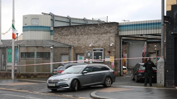 A PSNi officer stands inside a police tape with three vehicles visible - numberplates pixelated