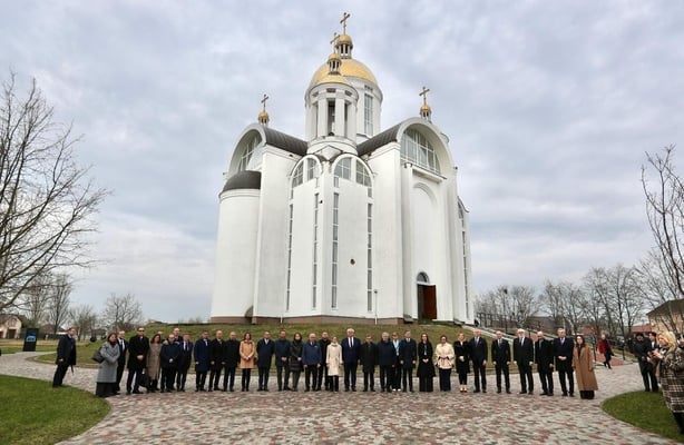 a large group of people line up for a photograph in front of a church building with a golden dome