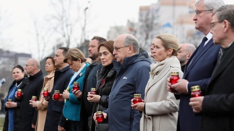 a line of people hold red tea lights