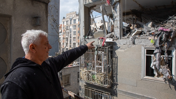A man gestures to a residential building struck by a drone, which killed one civilian in eastern Tehran, Iran