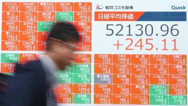 A man walks past an electronic quotation board displays numbers of the Nikkei Stock Average on the Tokyo Stock Exchange along a street in Tokyo on March 31, 2026.