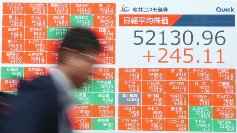 A man walks past an electronic quotation board displays numbers of the Nikkei Stock Average on the Tokyo Stock Exchange along a street in Tokyo on March 31, 2026.