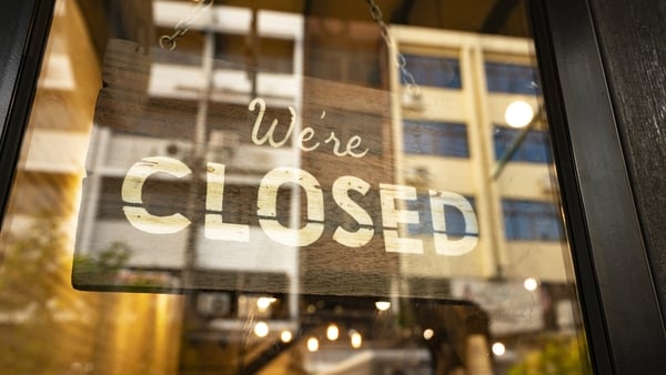 Closed sign hanging in business window by a string - crooked with glob of glue also attaching it to window
