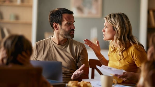 Frustrated parents talking about problematic financial bills during e-banking over a computer at home.