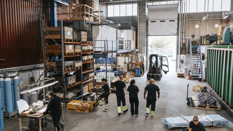 Rear view of male and female warehouse worker in black uniform discussing while walking in manufacturing factory