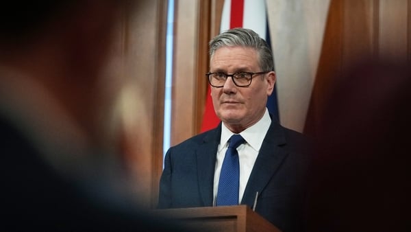 keir starmer speaks during a press conference with the union jack flag hanging behind me