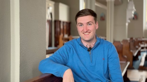 A young man smiles as he sits in a church in Co Carlow
