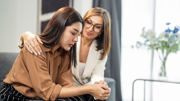 Two women share an emotional moment, as one supports the other with comforting gestures. Captured indoors, the scene conveys care and understanding in a warm and private setting. (Getty Images)