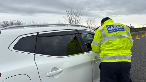 a garda speaks to a driver of a white suv type vehicle