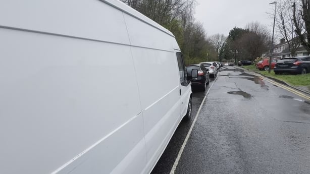 The side of a white transit van parked behind other cars