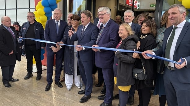Minister O'Brien cuts a blue ribbon flanked by other people