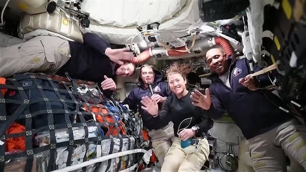 three men and a woman are pictured in uniform on board a space ship called Artemis 2