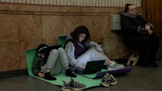 people sit on mats looking at laptops and tablets 