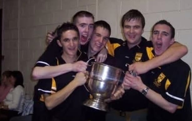 A group of young people holding a sports trophy and celebrating