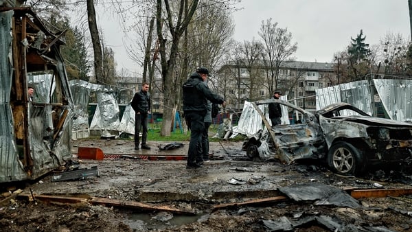 People stand near a wreckage of car at residential district after Russian drone-and-missile attack in Vyshneve, Ukraine