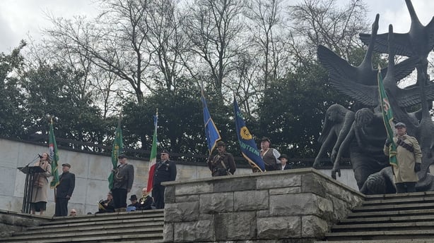People hold flags on the steps at the Garden of Remembrance