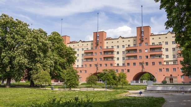 Wide view of the Karl-Marx-Hof in Vienna, Austria, seen across a green public park. The historic housing complex is a notable example of social architecture from the interwar period.