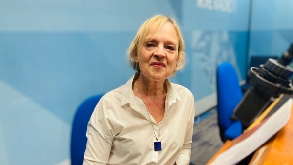 writer Liz McSkeane, in RTÉ Radio studio, sitting at mic with blue background, April 2026