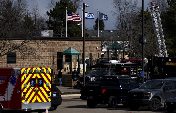 Law enforcement vehicles in the parking lot of Temple Israel as an Israeli flag blows in the wind