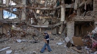 A woman walks among buildings destroyed in a joint attack by Israel and the United States in Tehran, Iran
