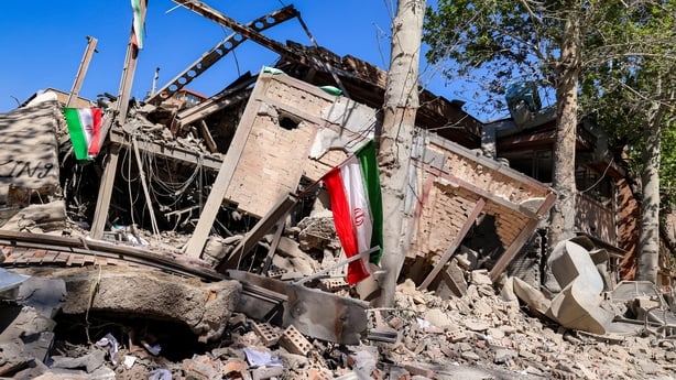 Iranian national flags are placed by the rubble of a collapsed building following strikes at Sharif University of Technology in Tehran