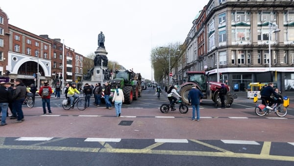 tractors block o'connell bridge in Dublin as people walk by